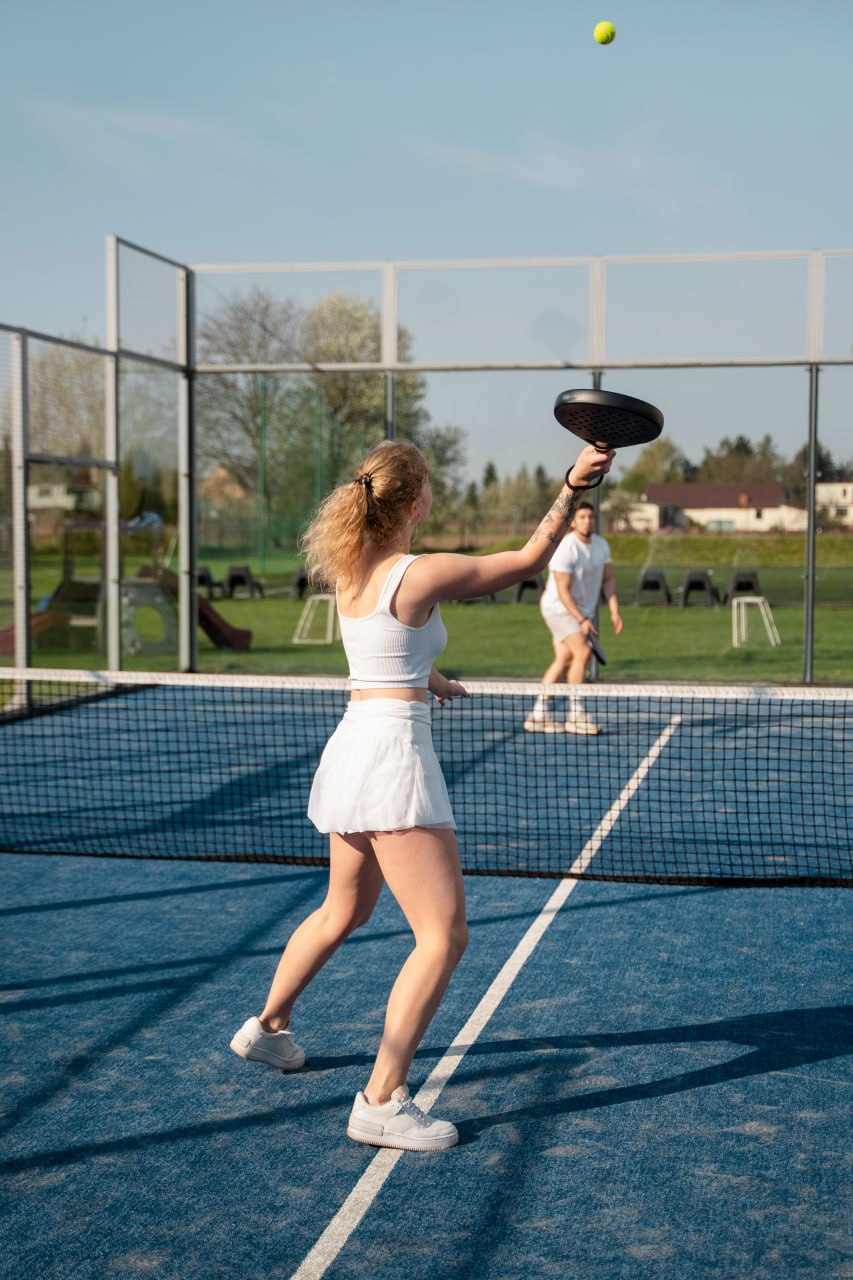 Padel player hitting the ball on a blue outdoor court