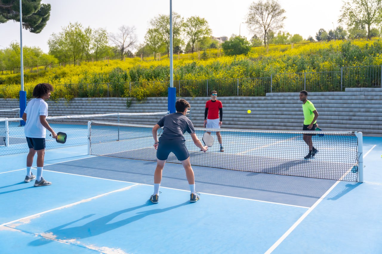 Pickleball doubles game on a blue outdoor court